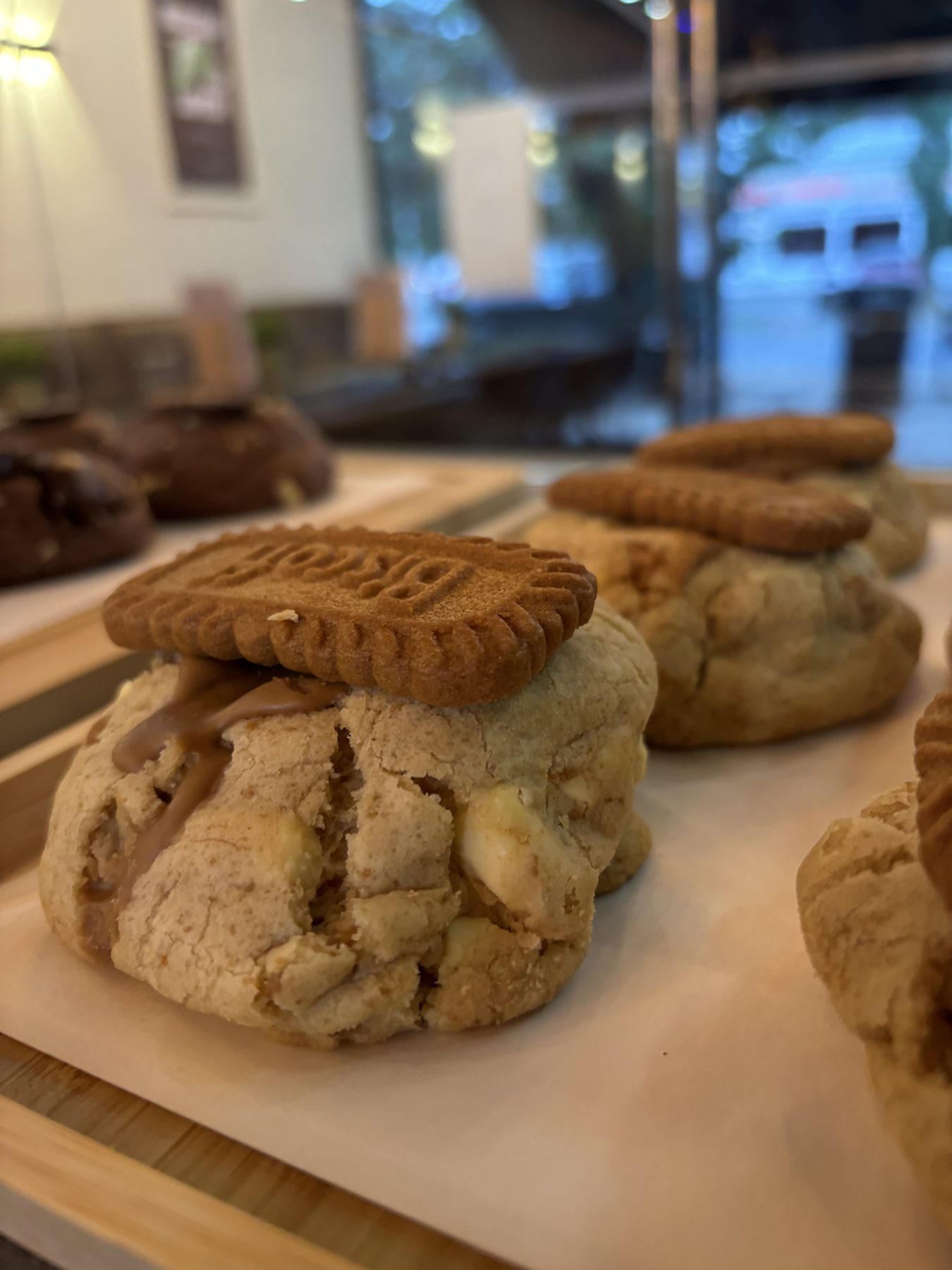 A Biscoff cookie on a wooden tray in the pastry case.