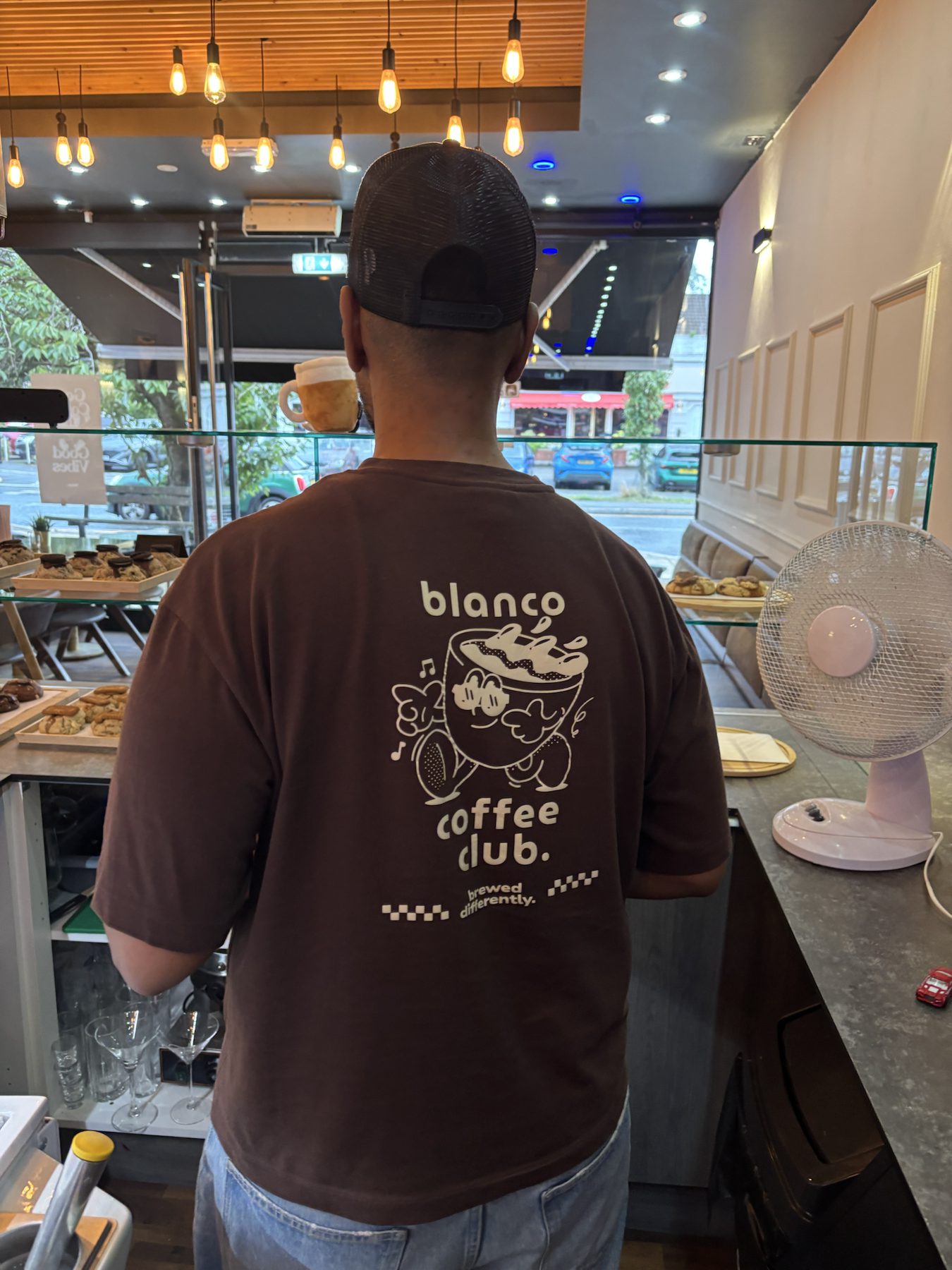 A barista at the counter wearing the Blanco coffee club tee.