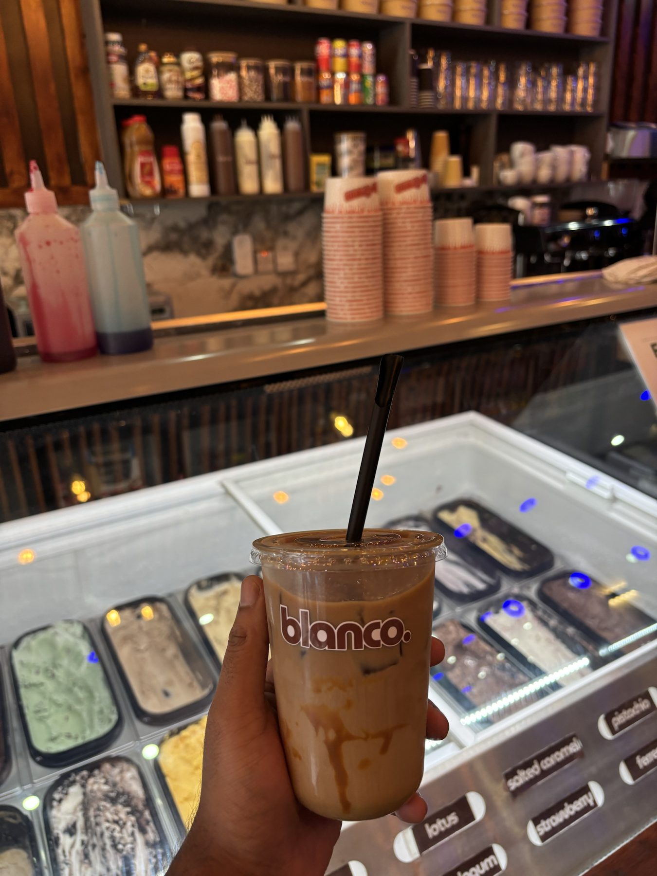 An iced Blanco latte in front of the gelato cabinet.