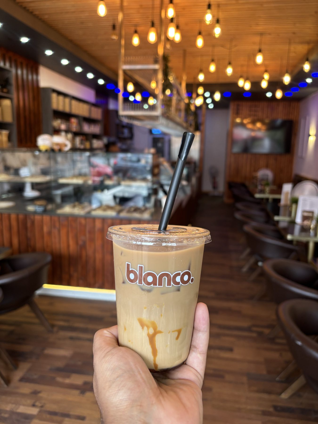 An iced Blanco latte held in the dining room under the hanging lights.